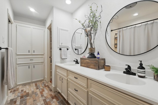 bathroom with double vanity, a sink, brick floor, and recessed lighting