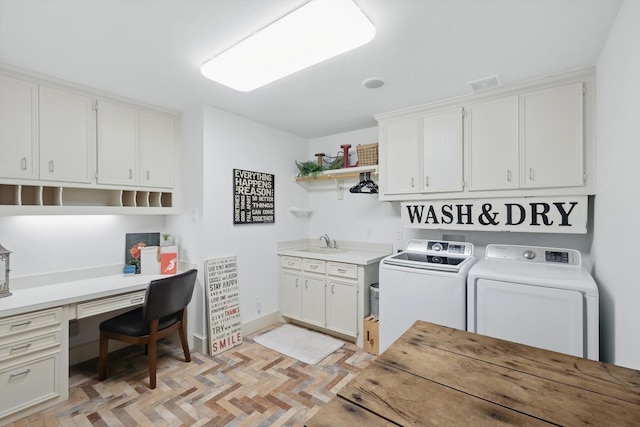 clothes washing area with a sink, visible vents, cabinet space, and washer and clothes dryer