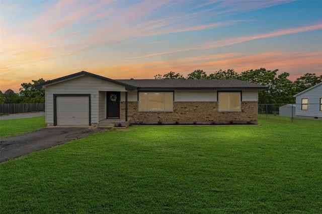 single story home with brick siding, aphalt driveway, fence, and a front yard