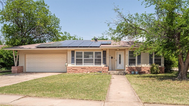 ranch-style home with a garage, a front lawn, and solar panels