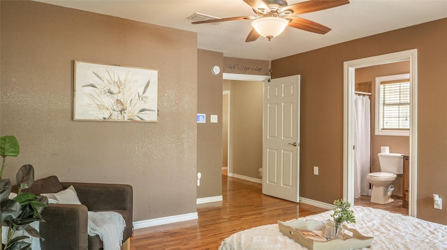 bedroom featuring baseboards, visible vents, wood finished floors, and ensuite bathroom