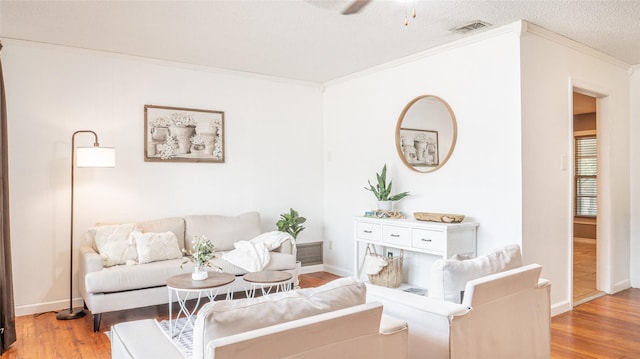 living area featuring ceiling fan, baseboards, ornamental molding, and wood finished floors