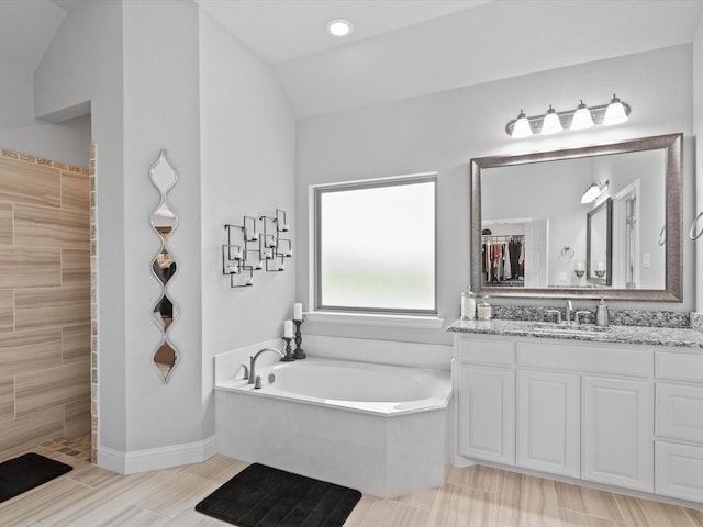 full bathroom featuring a bath, a tile shower, vanity, baseboards, and lofted ceiling