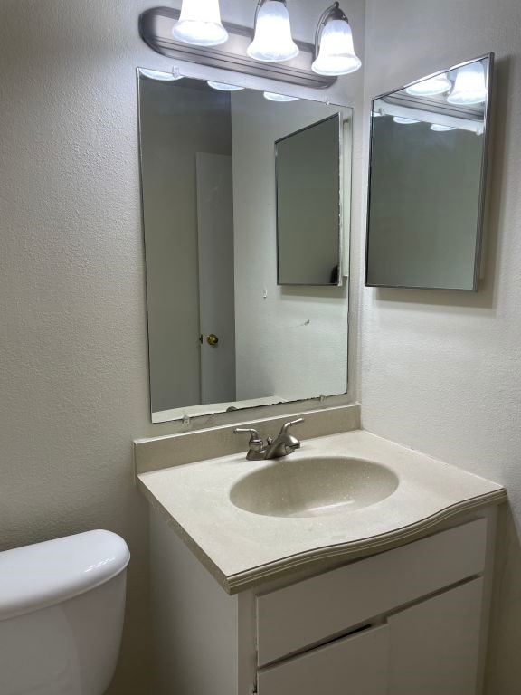 half bath featuring vanity and toilet