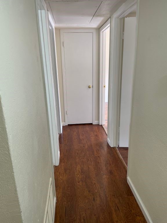 corridor featuring visible vents, attic access, dark wood-style flooring, and baseboards