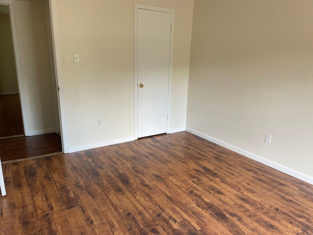 empty room featuring baseboards and dark wood-style floors