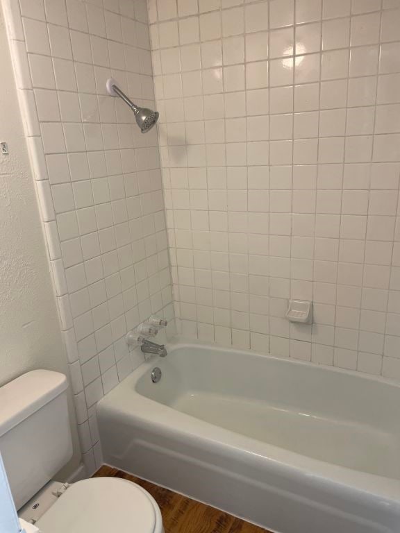 bathroom featuring bathing tub / shower combination, toilet, and wood finished floors