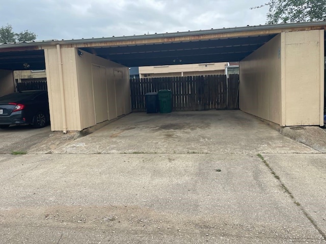 view of parking with fence, a carport, and concrete driveway