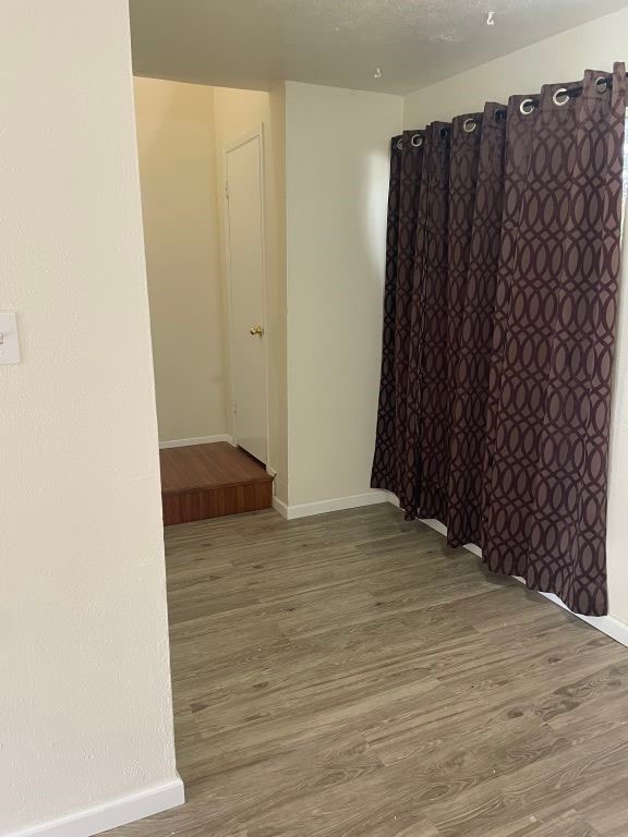 empty room with baseboards and wood finished floors