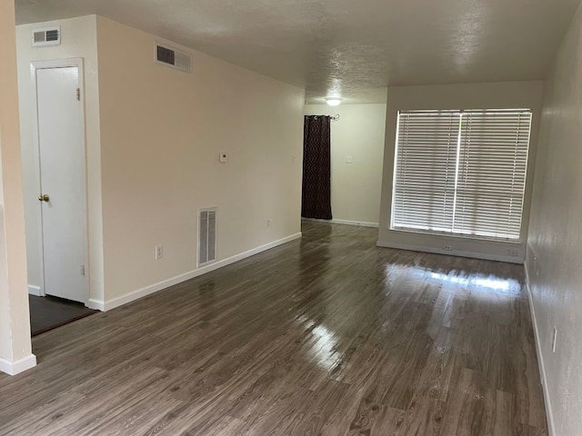 unfurnished living room featuring visible vents, dark wood finished floors, and baseboards