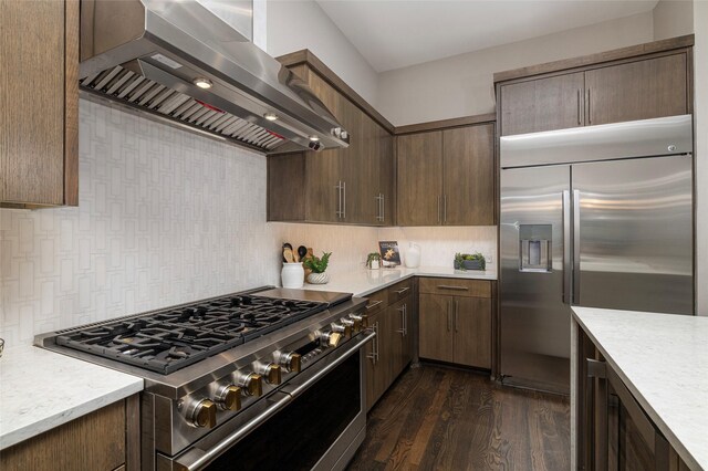 kitchen featuring dark wood-style floors, wall chimney range hood, light countertops, tasteful backsplash, and stainless steel appliances