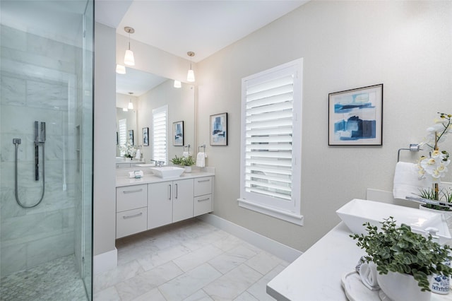 bathroom featuring vanity, marble finish floor, baseboards, and a tile shower