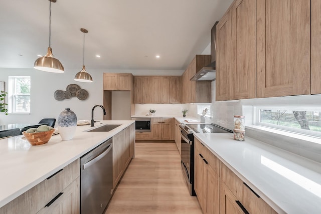 kitchen featuring light brown cabinetry, light countertops, a sink, light wood finished floors, and appliances with stainless steel finishes