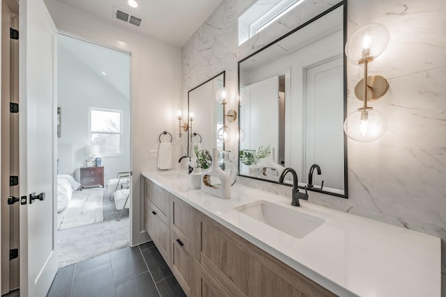 ensuite bathroom with a sink, ensuite bath, double vanity, and visible vents