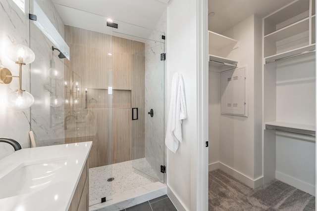 bathroom with a marble finish shower, baseboards, vanity, and a spacious closet