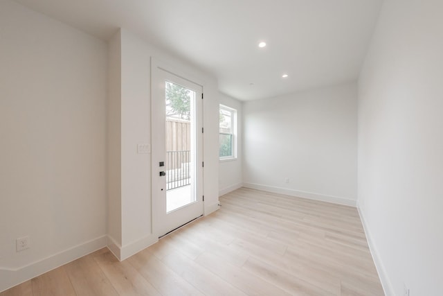 doorway to outside featuring baseboards, light wood-type flooring, and recessed lighting
