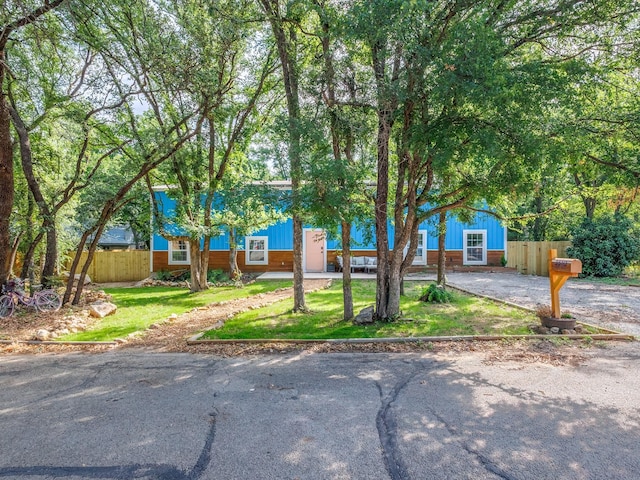view of front facade with fence, driveway, and a front yard