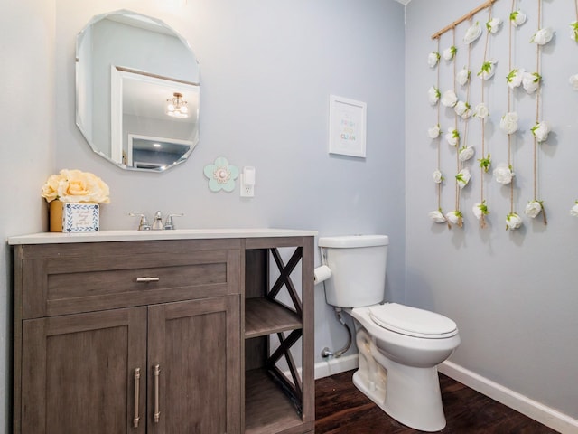 bathroom with baseboards, vanity, toilet, and wood finished floors