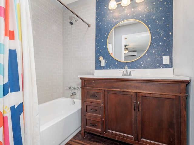 bathroom with ceiling fan, shower / bath combo, wood finished floors, vanity, and wallpapered walls