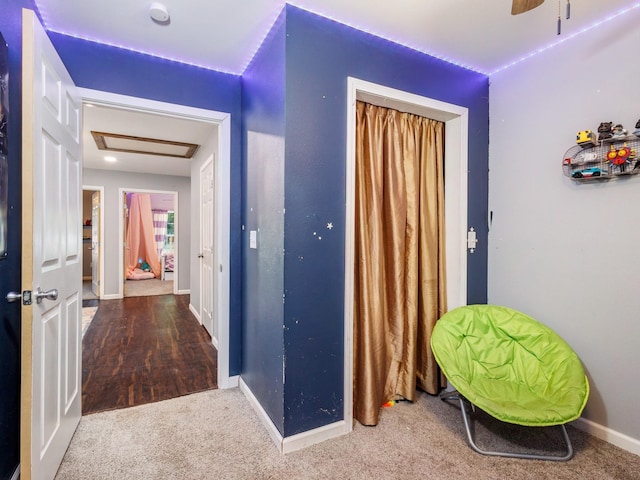 hall with carpet floors, baseboards, and attic access