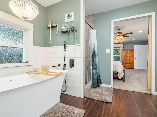 full bathroom with ceiling fan, a freestanding bath, a shower stall, and wood finished floors