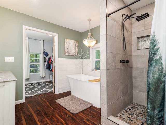bathroom with a freestanding bath, wood finished floors, a wealth of natural light, and tiled shower