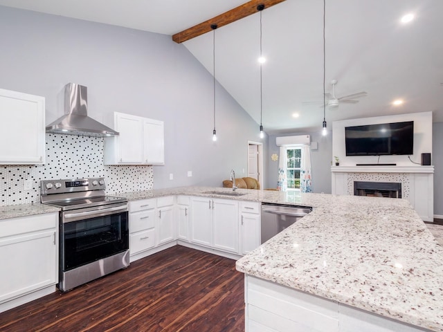 kitchen featuring light stone counters, a sink, wall chimney exhaust hood, stainless steel appliances, and open floor plan