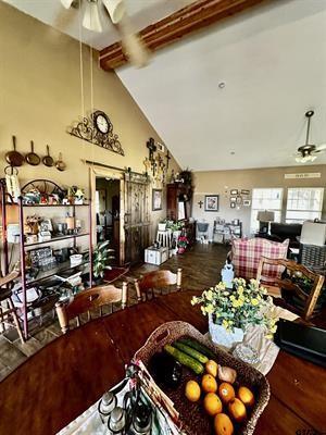 dining area with a barn door, beamed ceiling, a ceiling fan, and wood finished floors
