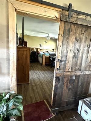 corridor with a barn door and dark wood finished floors