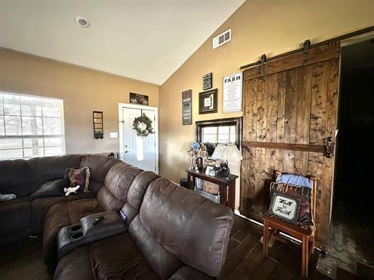 living area with a wealth of natural light, dark wood-style floors, a barn door, and visible vents