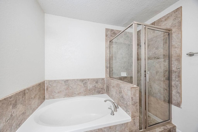 full bathroom featuring a textured ceiling, a shower stall, and a garden tub