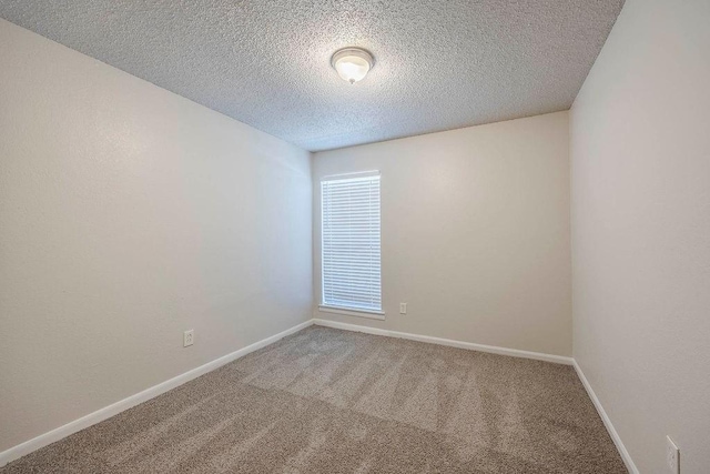 carpeted spare room with baseboards and a textured ceiling