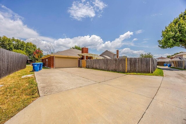 view of property exterior with brick siding, fence, and a garage