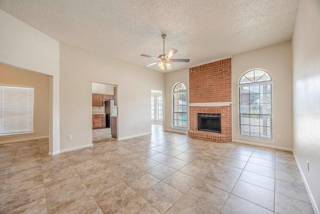 unfurnished living room featuring a healthy amount of sunlight, baseboards, a ceiling fan, and a textured ceiling