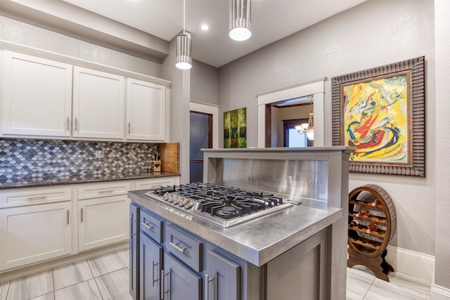 kitchen with decorative backsplash, a kitchen island, decorative light fixtures, stainless steel gas cooktop, and white cabinetry