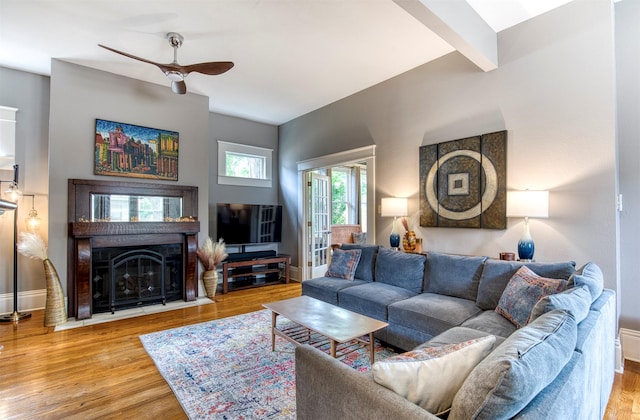 living area with baseboards, ceiling fan, wood finished floors, and a fireplace