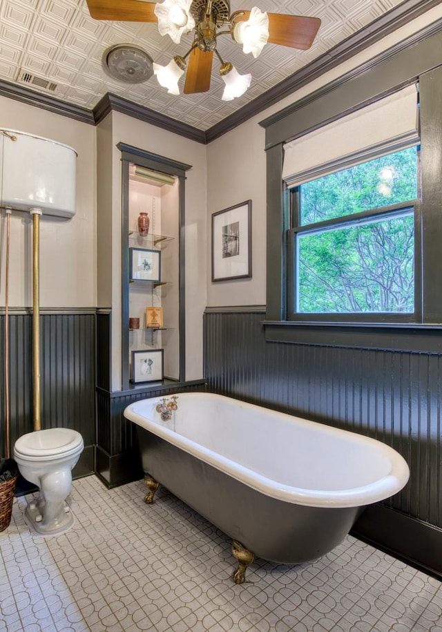 full bath featuring crown molding, a wainscoted wall, an ornate ceiling, toilet, and an inviting chandelier