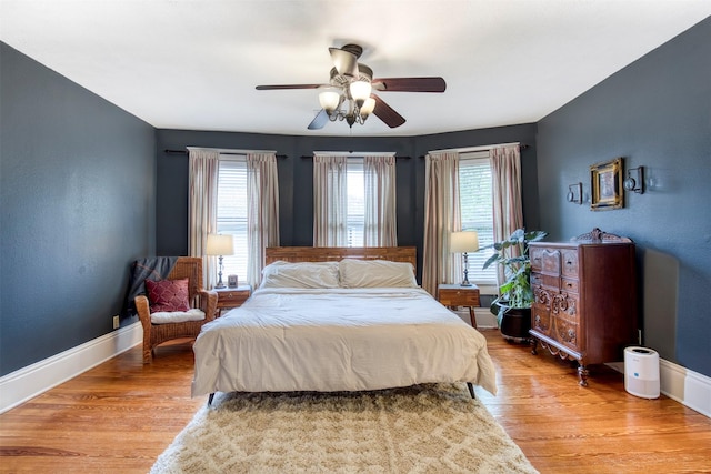 bedroom featuring baseboards, multiple windows, and light wood-type flooring