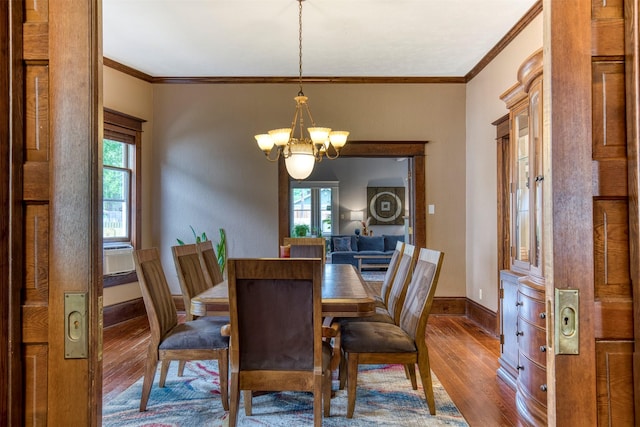dining area with crown molding, plenty of natural light, wood-type flooring, and a notable chandelier