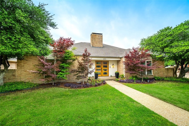 view of front of property with brick siding, a front yard, french doors, and a chimney