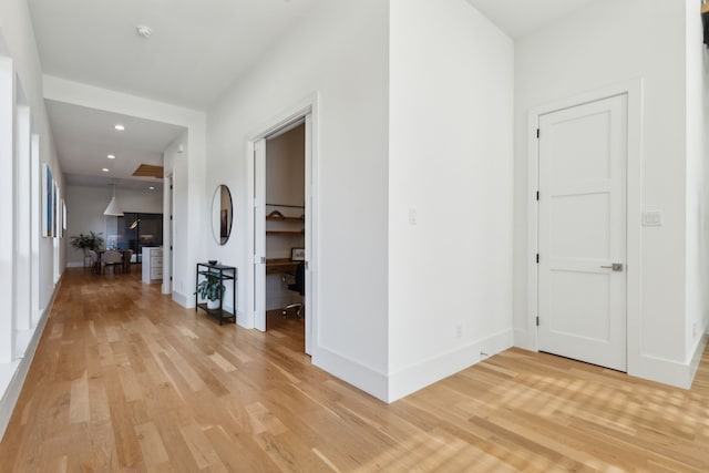 hall featuring baseboards, recessed lighting, and light wood finished floors