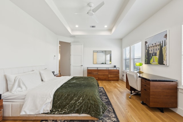 bedroom with a raised ceiling, recessed lighting, baseboards, light wood-type flooring, and visible vents