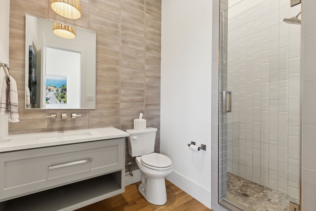 full bath featuring vanity, wood finished floors, toilet, tile walls, and a shower stall