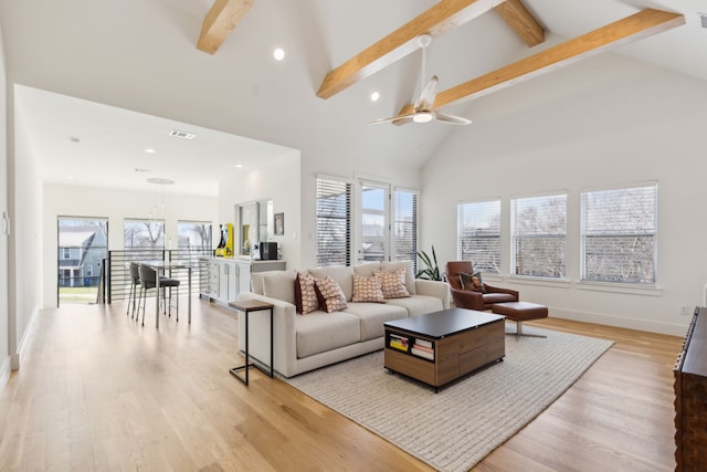living area with recessed lighting, a ceiling fan, a wealth of natural light, and beamed ceiling