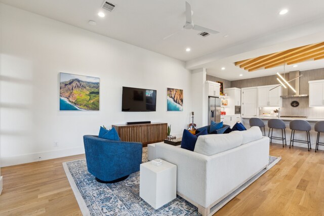 living area with a ceiling fan, visible vents, light wood-type flooring, baseboards, and recessed lighting