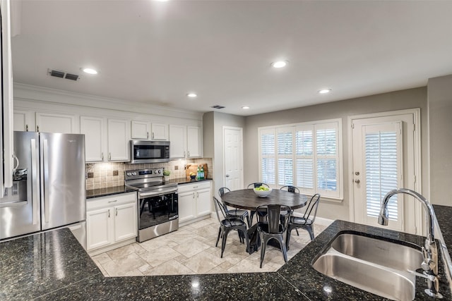 kitchen featuring a sink, stainless steel appliances, white cabinetry, tasteful backsplash, and visible vents