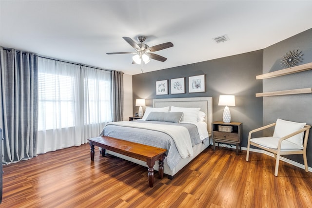 bedroom with ceiling fan, visible vents, and wood finished floors