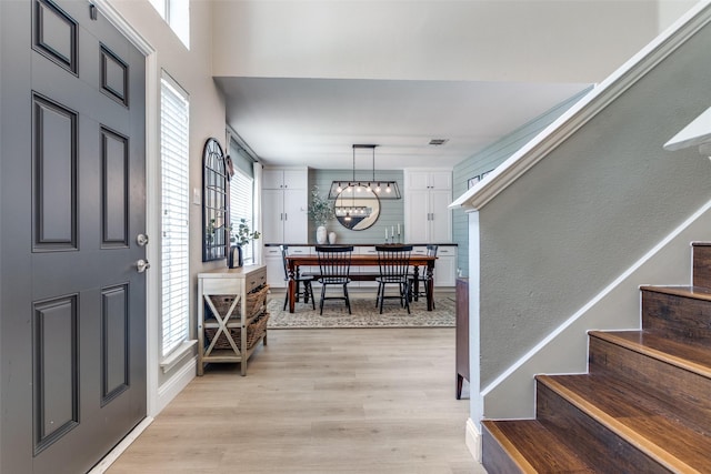 foyer entrance with an inviting chandelier, baseboards, light wood finished floors, and stairs