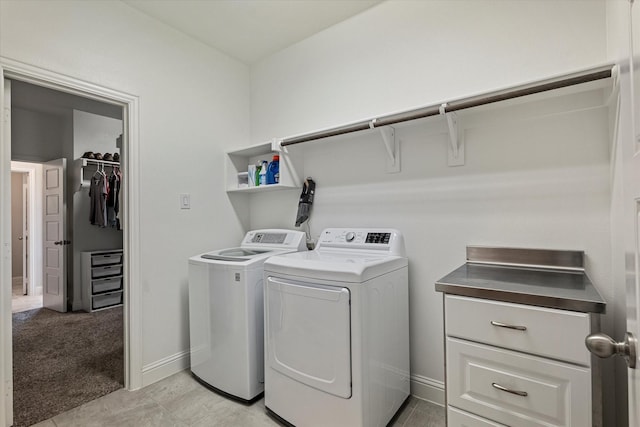 clothes washing area featuring baseboards, laundry area, light colored carpet, and washer and clothes dryer