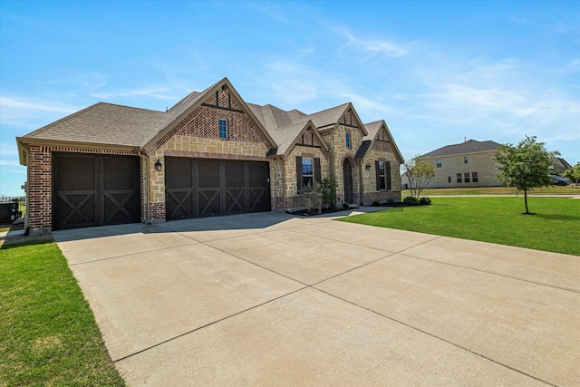 french provincial home with concrete driveway, an attached garage, a front yard, and brick siding